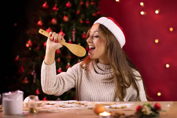Chica en santa hat canta haciendo galletas de Navidad en estudio rojo decoración de Navidad — Foto de Stock