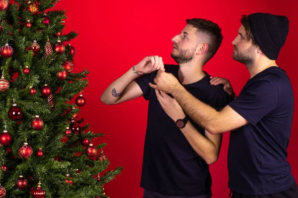 Atractiva pareja homosexual masculina decorando árbol de Navidad juntos, Feliz Navidad — Foto de Stock
