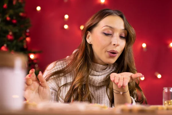 Momento mágico de Navidad. Mujer bonita hace galletas, sopla lejos la decoración de polvo — Foto de Stock