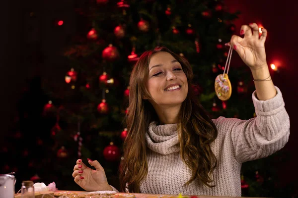 Melko pitkätukkainen brunette tyttö katsoo juuri koristeltu joulun evästeet — kuvapankkivalokuva
