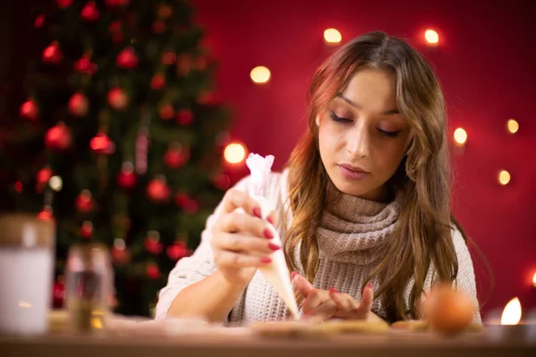 Panadería de Navidad. bonita chica morena decorando galletas de jengibre de Navidad — Foto de Stock