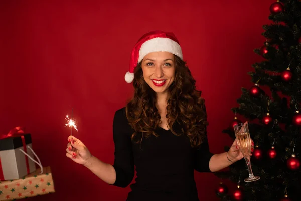 Mujer bastante sonriente con regalos de Navidad chispeante árbol sobre fondo rojo, espacio de copia —  Fotos de Stock