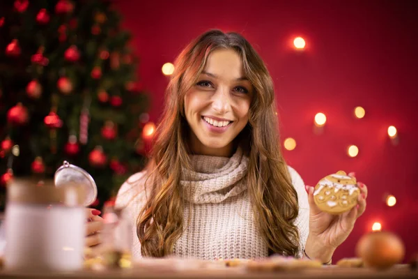 Bastante sonriente chica morena decoración recién horneado galletas de Navidad — Foto de Stock