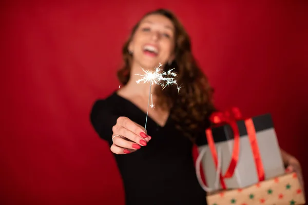 Celebración festiva. Mujer con regalos de Navidad y bengala ardiente en foco — Foto de Stock
