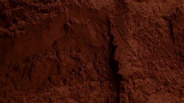 Kakao tozunun içine düşen siyah çikolata parçaları sıçrama yapıyor, ağır çekim.