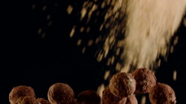 Koyu çikolata trüf mantarları uçuyor kakao tozu bulutuyla çarpışıyor, yakın plan.