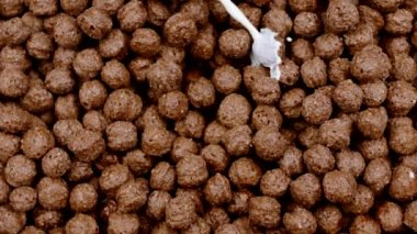 Çikolatalı mısır toplarına dökülen ve yavaş çekimde sıçrayan yakın plan süt.