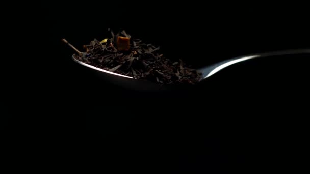 Φυτικό τσάι φύλλων που πέφτει από το κουτάλι σε αργή κίνηση απομονώνονται σε μαύρο φόντο — Αρχείο Βίντεο