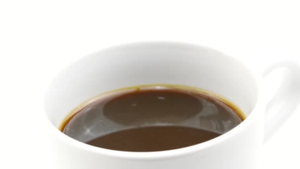 Leche vertiendo en la taza con café sobre fondo blanco en cámara lenta, primer plano — Vídeos de Stock