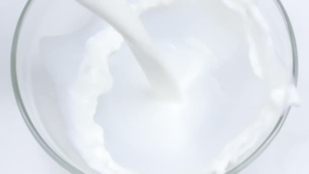 Κοντινό οργανικό φρέσκο γάλα χύνεται σε γυάλινο μπολ σε αργή κίνηση, τρώγοντας — Αρχείο Βίντεο