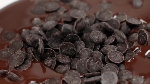 Callejuelas de chocolate cae en chocolate fundido oscuro, primer plano, cámara lenta — Vídeos de Stock