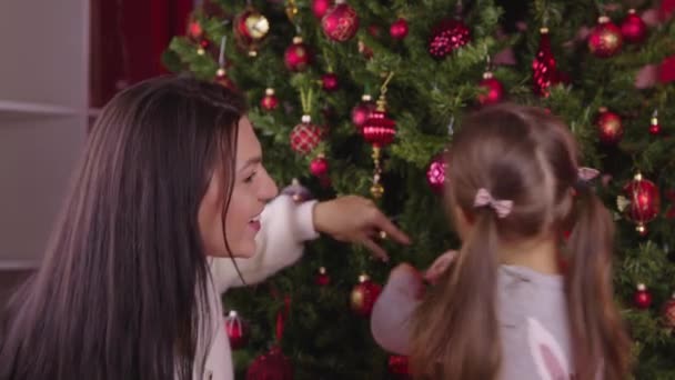 Young beautiful mother and cute little daughter decorating Christmas tree, xmas — Stock Video