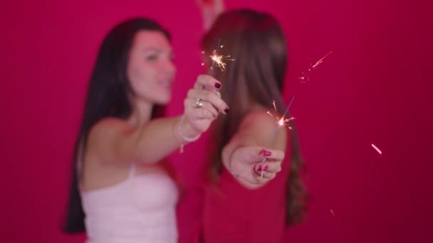 Dos mujeres jóvenes enamoradas disfrutan de la atmósfera navideña, besando y quemando chispas — Vídeo de stock