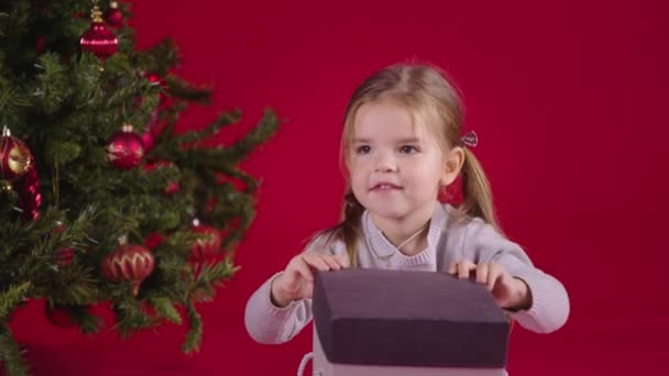 Julmirakel. Glad liten flicka öppnar julklapp med magiskt ljus inuti — Stockvideo