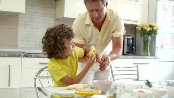 Дід і онук роблять десерт разом, хлопчик допомагає дідусю на кухні — стокове відео