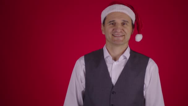 산타 모자를 쓴 남자가 크리스마스 화환을 목에 걸고 있습니다 — 비디오