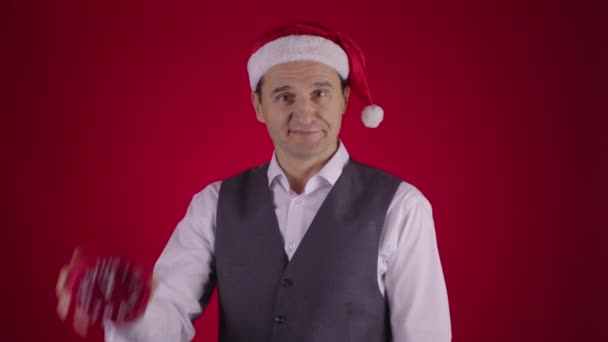 Fröhlicher Mann mit Weihnachtsmütze, der auf Uhr zeigt, erinnert an Minuten vor Silvester — Stockvideo