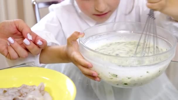 Cerca de poco ayudante de cocina con la madre, chica mezcla relleno de pastel con batidor — Vídeos de Stock