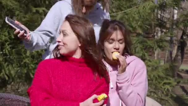 Chicas jóvenes se divierten en un picnic, comer maíz y tomar selfies y reír. — Vídeos de Stock