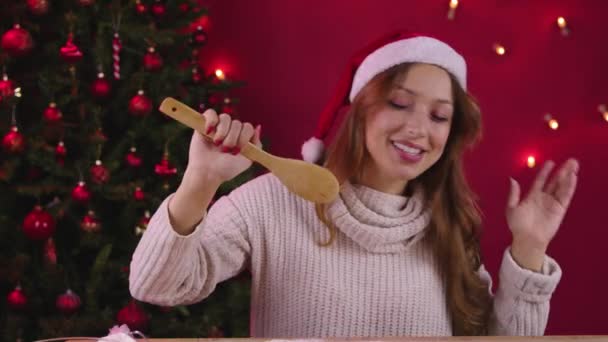 Young pretty woman have fun on Christmas kitchen, sings xmas songs using spatula — Stock Video