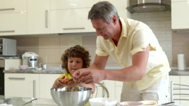 Mutlu baba ve tatlı oğul birlikte yemek pişirir. Yumurtaları büyük hamur kaselerine kırarlar.