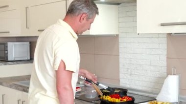 Yakışıklı olgun adam sebzeleri ızgarada kızartıyor, sağlıklı vejetaryen yemeği pişiriyor.