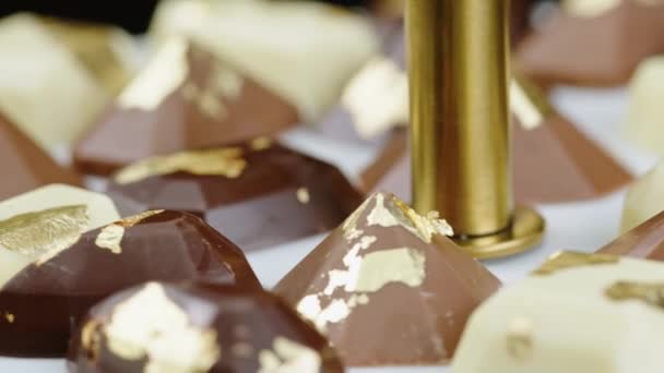 Closeup set van premium chocolade snoepjes met goud folie decoratie roterende — Stockvideo