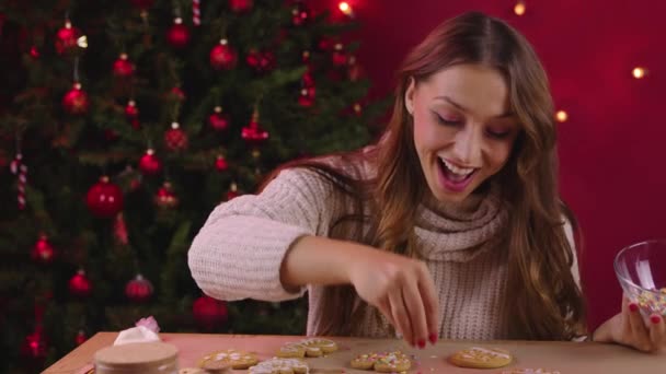 Pretty brunette girl decorating christmas cookies in Xmas decoration Self-gifter — Stock Video
