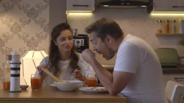 İki insan aile mutfağında salata yer ve taze sıkılmış meyve suyu içerler.