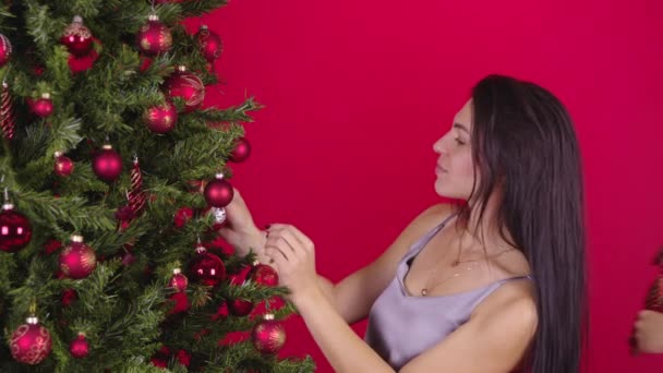 Lesbian couple of two young girls hanging toy balls on Christmas Tree Together — Stock Video