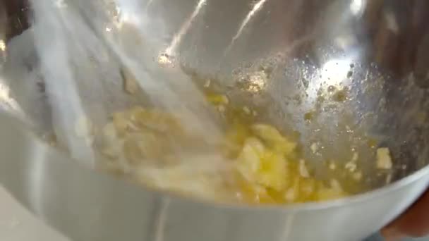Закрыть взбивая масляные яйца для наполнения теста венчиком в железную миску, приготовления пищи — стоковое видео