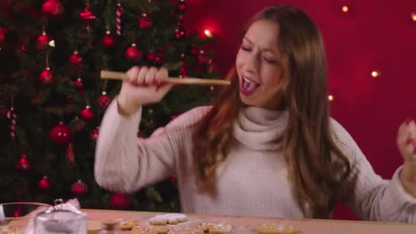 귀엽고 긴 머리 소녀가 크리스마스 장식에 손으로 만든 생강 빵 장식을 하고 있다. — 비디오