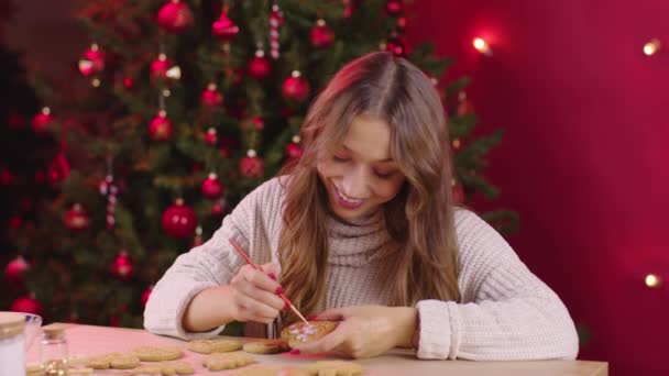 Young smiling woman making Christmas bakery paints festive ginger cookies — Stock Video