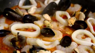 Paella tavada pişirilir, lezzetli deniz ürünlerine midye eklenir.
