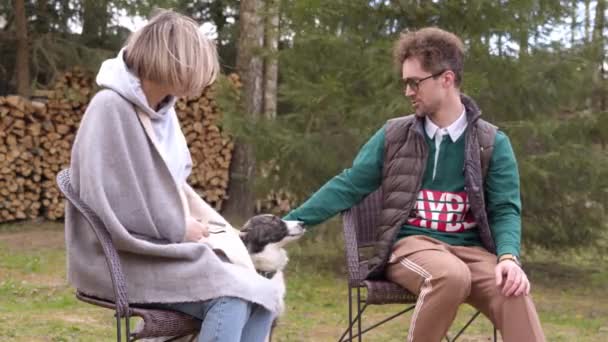 Szczęśliwi przyjaciele z psem korzystających kemping, siedzi przy ognisku czatując na świeżym powietrzu — Wideo stockowe