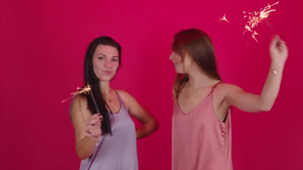 Lesbisches Paar von zwei hübschen jungen Mädchen, die Spaß mit brennenden Wunderkerzen haben — Stockvideo