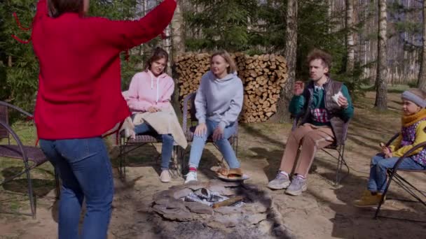 Funny adult outdoor games. Joyful friends sitting around campfire playing games — Stock Video