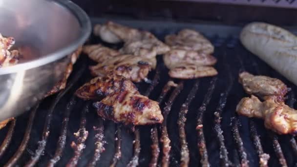 Mans ręka w rękawicy zdejmuje grillowane mięso kurczaka z szczypcami do gotowania z siatki — Wideo stockowe