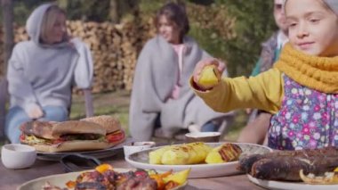 Barbekü partisinde beş çekici insan. Kız ananas ızgarasını masadan alır.