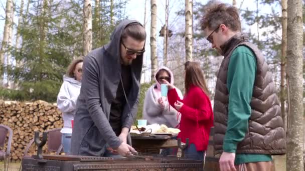 Mężczyźni grillują mięso na łonie natury wiosną słonecznego dnia. Ludzie komunikują się na pikniku. — Wideo stockowe
