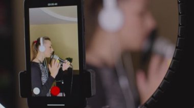Mikrofonda şarkı söyleyen, müzik dersi veren güzel bir seslendirme sanatçısı.