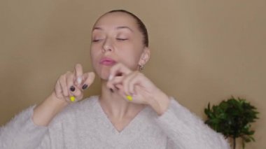 Genç bayan blogcu evde yüz egzersizi yapıyor, canlı yayın yapıyor.