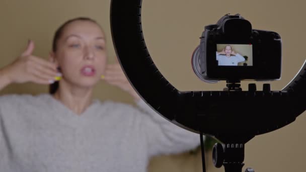 Söt bloggare praktiserar ansiktyoga, visar hudmassage linjer, online-motion — Stockvideo