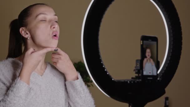 Young blogger doing skin fitness exercises for face contour, broadcasting — Stock Video