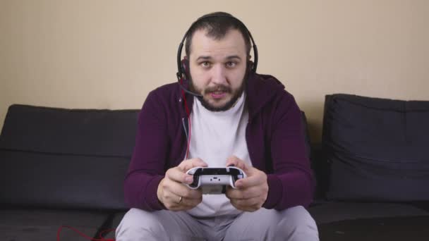 Jeune beau gamer masculin avec casque jouer jeu vidéo en ligne tenant joystick — Video