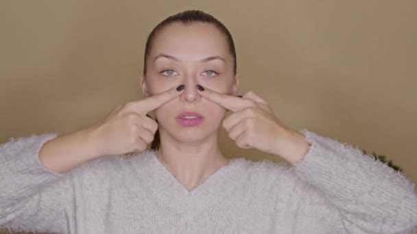 Młoda blogerka ćwiczy jogę na twarzy, pokazując linie do masażu skóry — Wideo stockowe