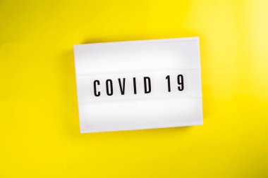 COVID 19, sarı arka planda ışık kutusu ile ilgili bir kelime izole edildi. kriz, karantina