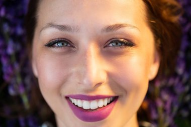 Güzel, gülümseyen bir kız. Mor çiçekli eflatun dudaklı.