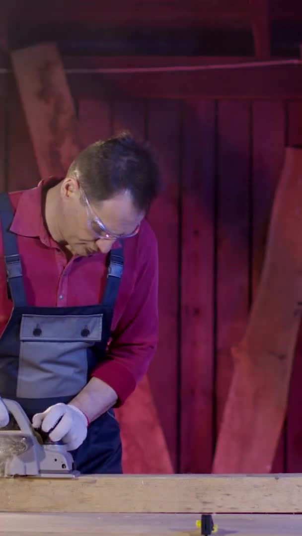 Vertikaler Schuss Männlicher Tischler reinigt Oberfläche von Holzbalken mit Elektrohobel in Werkstatt — Stockvideo