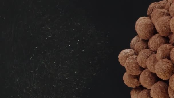 Vertical video Primer plano oro brillo polvo vierte a montón de trufas de chocolate sobre fondo negro — Vídeos de Stock